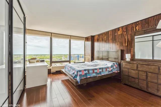 a large bedroom with a bed and large window with wooden floor