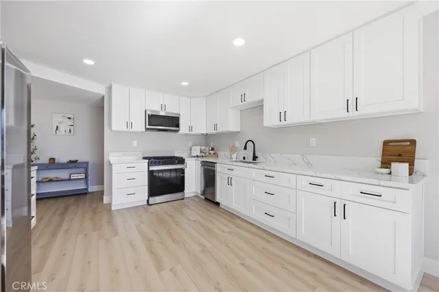 a kitchen with granite countertop white cabinets and stainless steel appliances