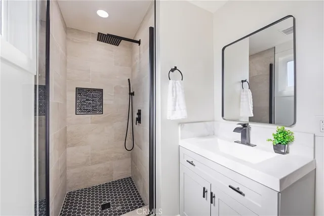 a bathroom with a sink shower and a mirror