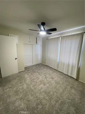an empty room with a ceiling fan and window