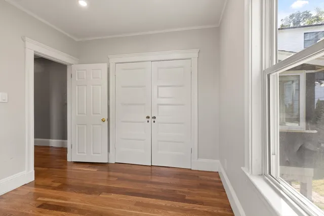a view of an empty room with wooden floor and a window