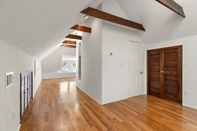 a view of an empty room with closet and wooden floor