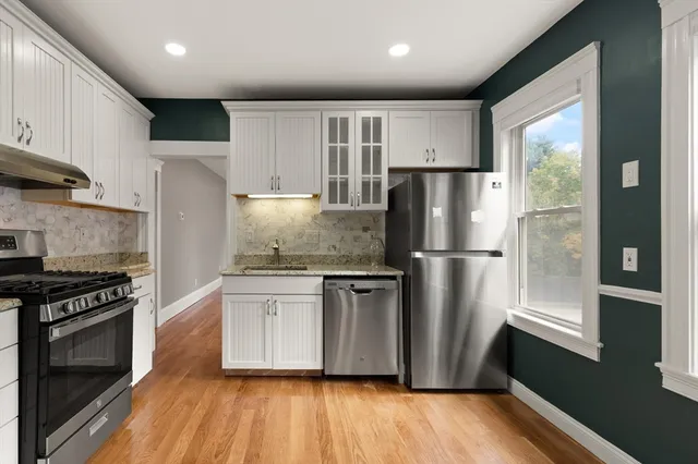 a kitchen with stainless steel appliances granite countertop a refrigerator a stove a sink and a microwave