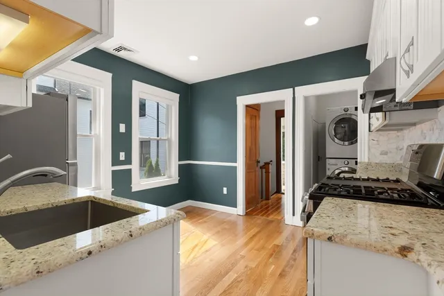a kitchen with granite countertop a sink and a stove top oven with wooden floor