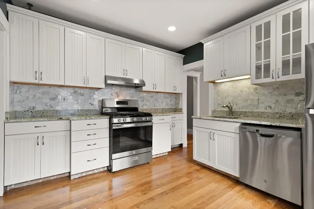 a kitchen with granite countertop white cabinets and stainless steel appliances
