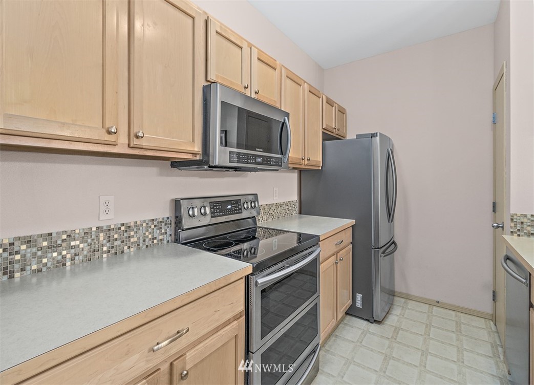 3012 Southeast 8th Place, Unit 1117 Renton, WA 98058 - Photo 12 of 40 a kitchen with stainless steel appliances granite countertop white cabinets a refrigerator and a stove