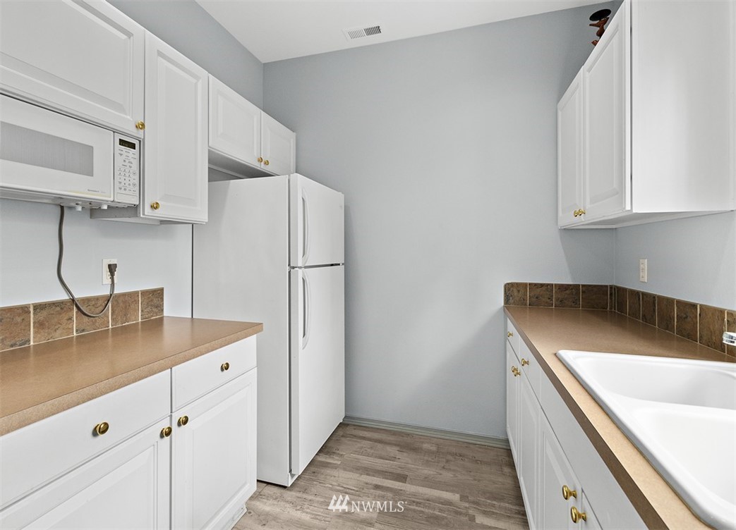 3012 Southeast 8th Place, Unit 1117 Renton, WA 98058 - Photo 36 of 40 a kitchen with stainless steel appliances granite countertop white refrigerator sink and cabinets