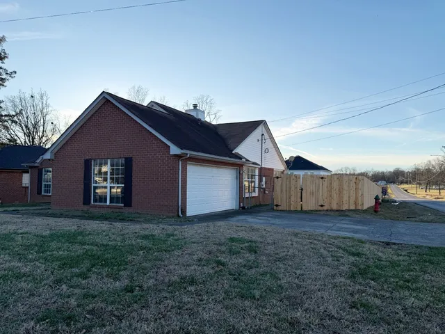 a house that has a big yard and large trees with wooden fence