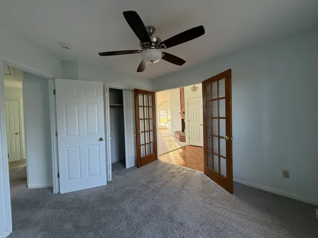 a view of a livingroom with a ceiling fan & windows