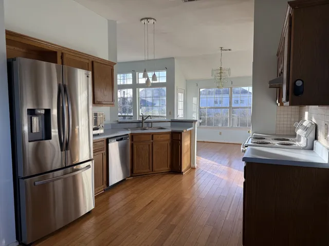 a kitchen with stainless steel appliances granite countertop a refrigerator a sink dishwasher a stove with wooden floor and cabinets