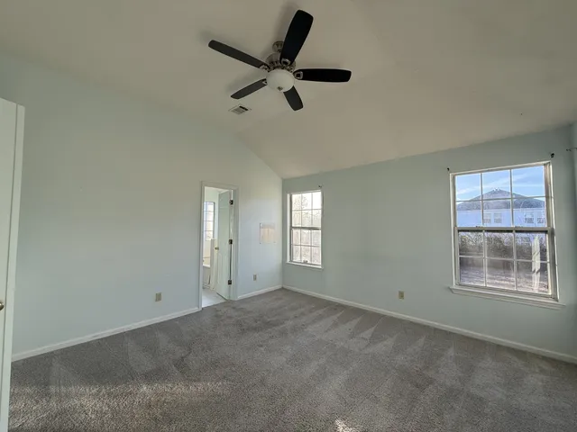 a view of a livingroom with a ceiling fan & windows