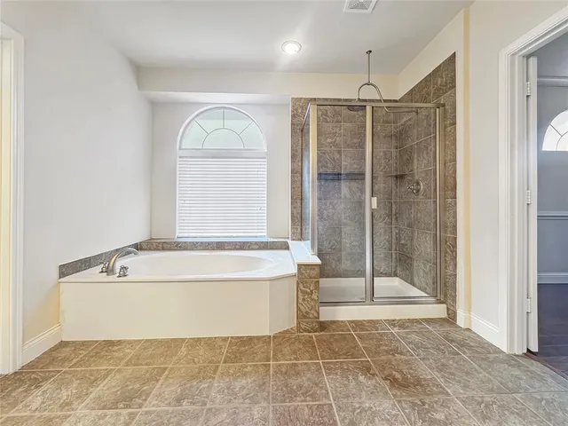 a bathroom with a tub a window and a glass door shower