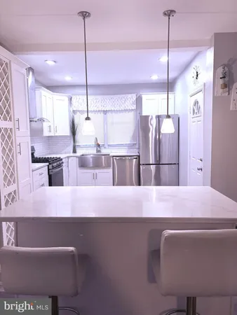 a kitchen with kitchen island stainless steel appliances a refrigerator a sink and a cabinets