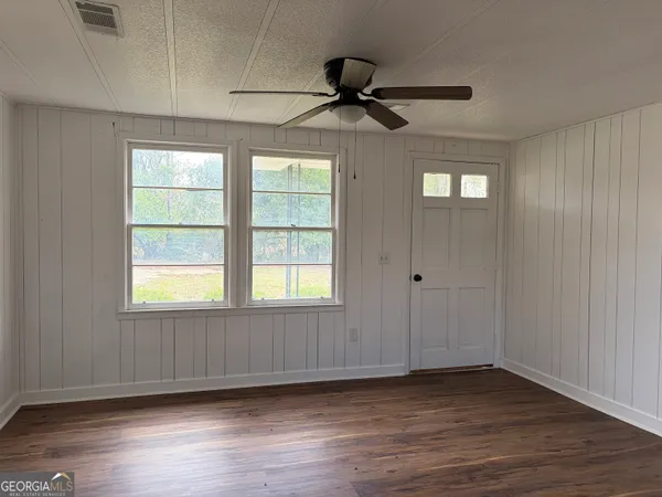 a view of an empty room with wooden floor and a window