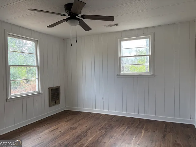 a view of an empty room with a window and wooden floor