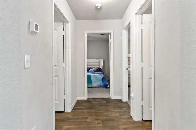 a view of a hallway with wooden floor and a bathroom