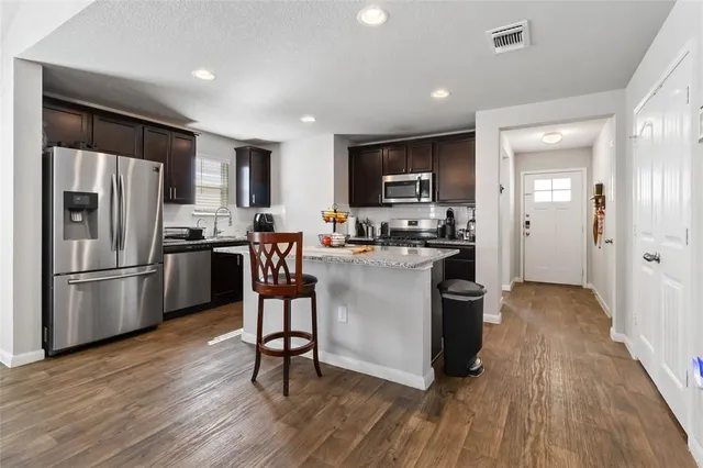 a kitchen with stainless steel appliances a refrigerator a stove a sink dishwasher and a dining table with wooden floor