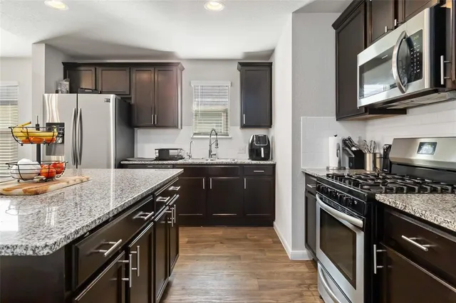 a kitchen with stainless steel appliances granite countertop a stove microwave refrigerator and sink