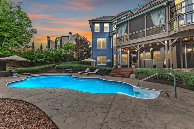 a view of a swimming pool with a bench and lawn chairs under an umbrella