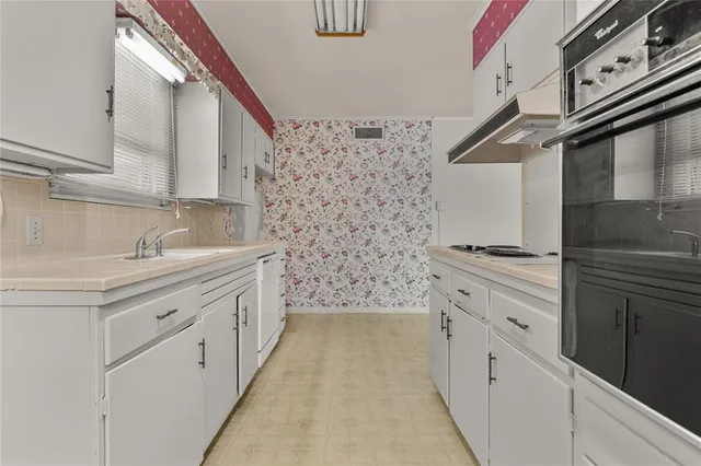 a kitchen with a stove and a sink with cabinets