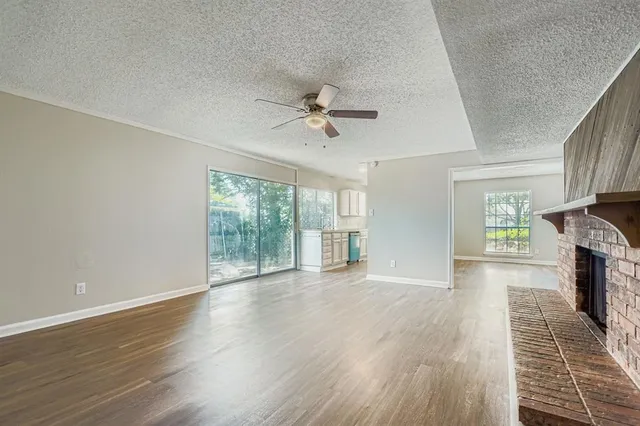 an empty room with wooden floor a chandelier fan and windows