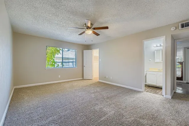 an empty room with windows and fan chandelier fan
