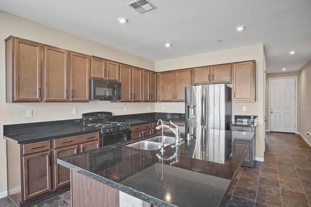 a kitchen with stainless steel appliances granite countertop a refrigerator and a sink