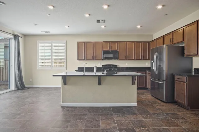 a kitchen with granite countertop a refrigerator a sink a stove a microwave and cabinets