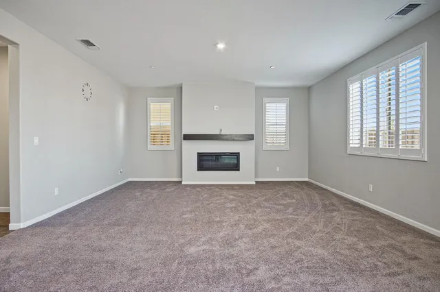 an empty room with windows & fireplace