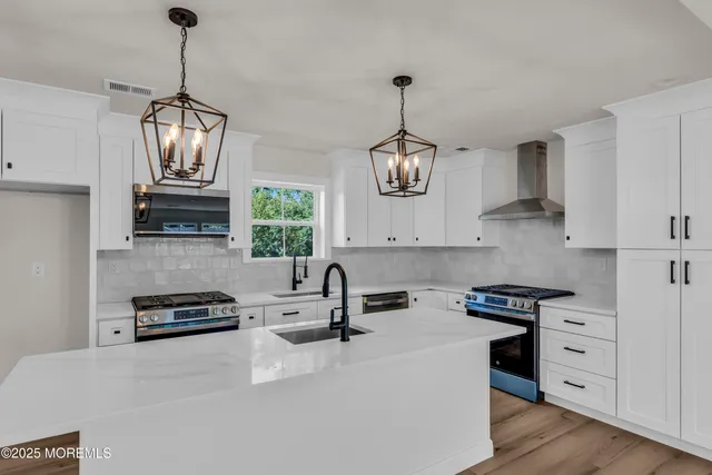 a kitchen with stainless steel appliances a stove a sink dishwasher a microwave oven with cabinets and wooden floor