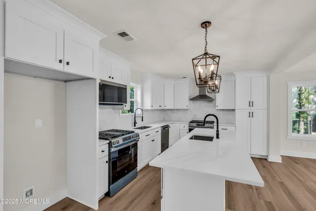a kitchen with kitchen island granite countertop a sink cabinets a window and stainless steel appliances