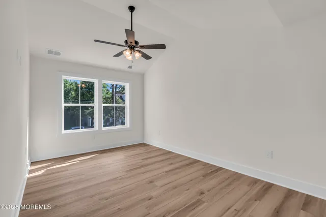 a view of empty room with wooden floor and ceiling fan