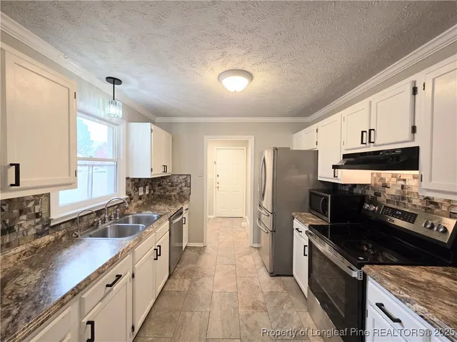 a large kitchen with stainless steel appliances granite countertop a stove a sink and a refrigerator
