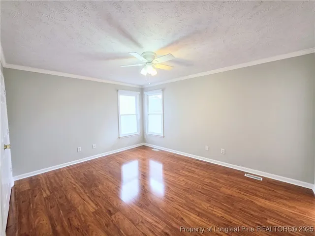 a view of an empty room with window and wooden floor