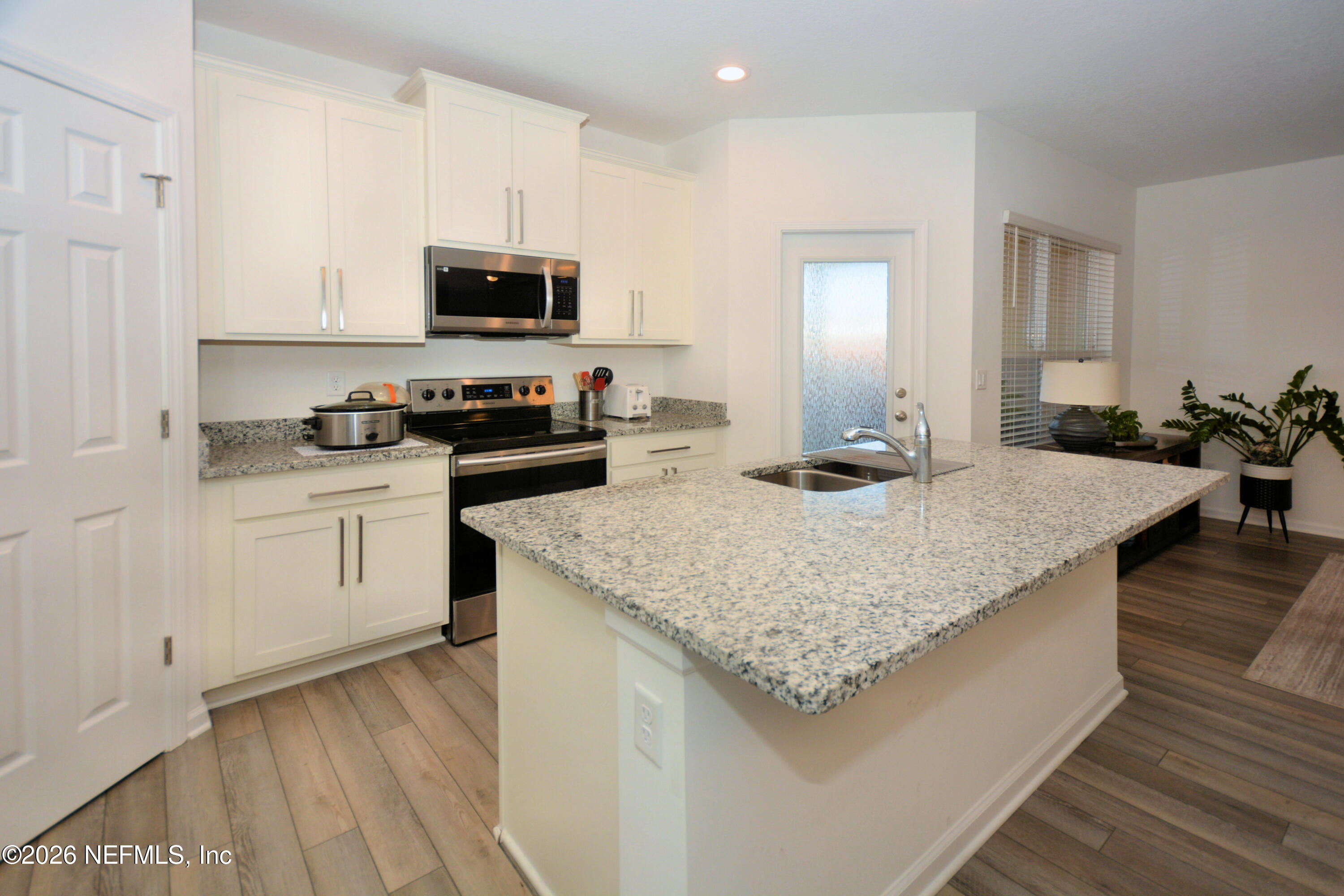 1688 Sanctuary Way Fleming Island, FL 32003 - Photo 12 of 35 a kitchen with granite countertop stainless steel appliances a stove top oven a sink a counter space and cabinets
