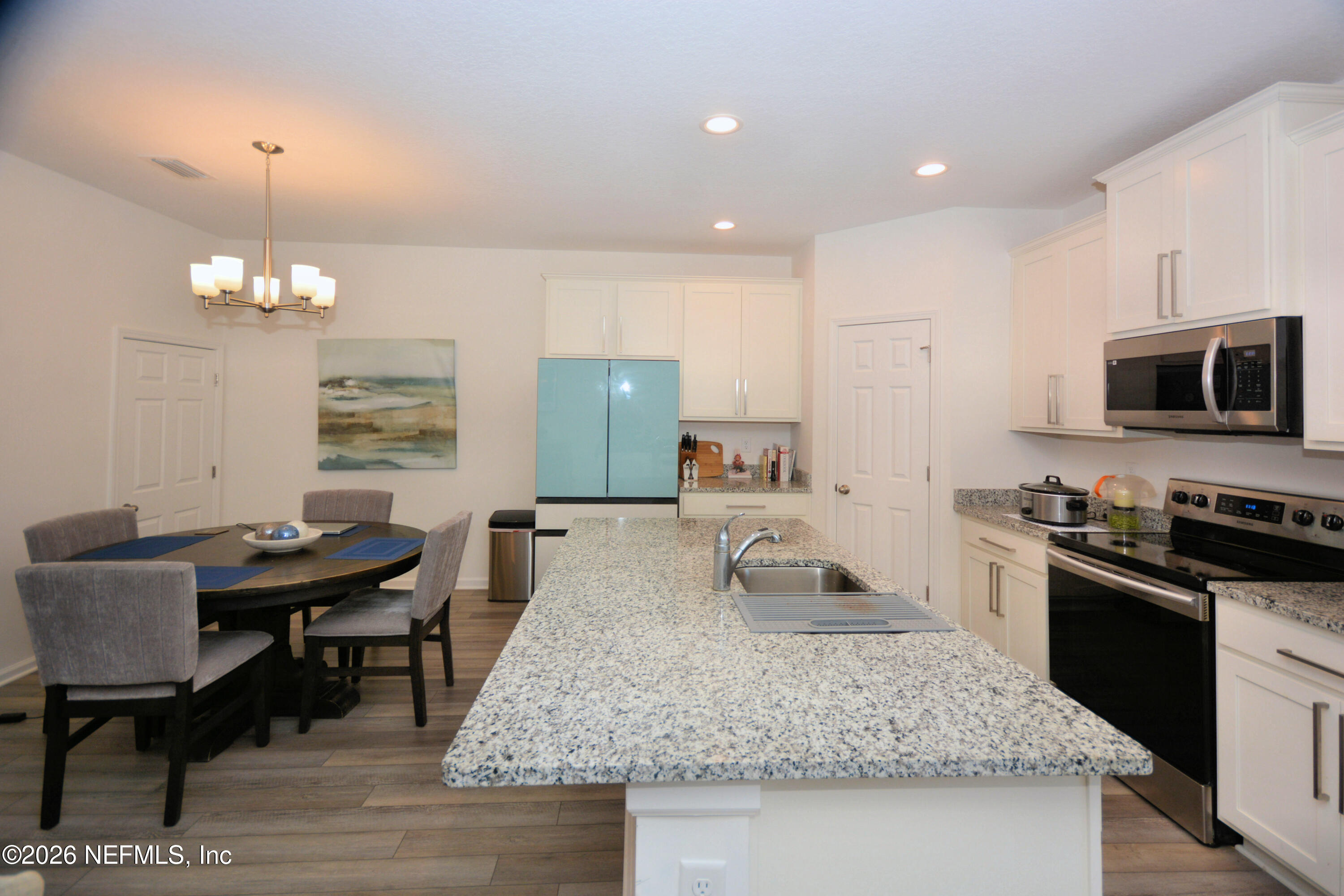 1688 Sanctuary Way Fleming Island, FL 32003 - Photo 9 of 35 a kitchen with sink refrigerator dining table and chairs