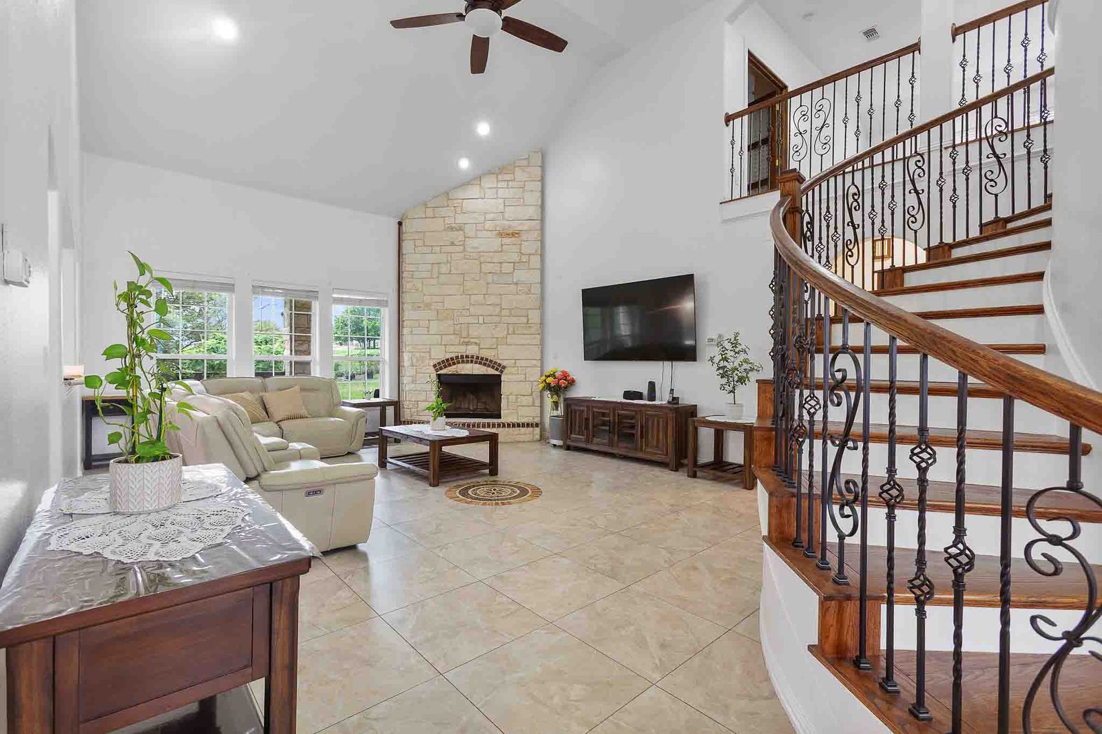 323 Woodbrook Trail Buda, TX 78610 - Photo 15 of 40 Two-story living area with a grand curved staircase featuring wrought iron balusters and a wood handrail