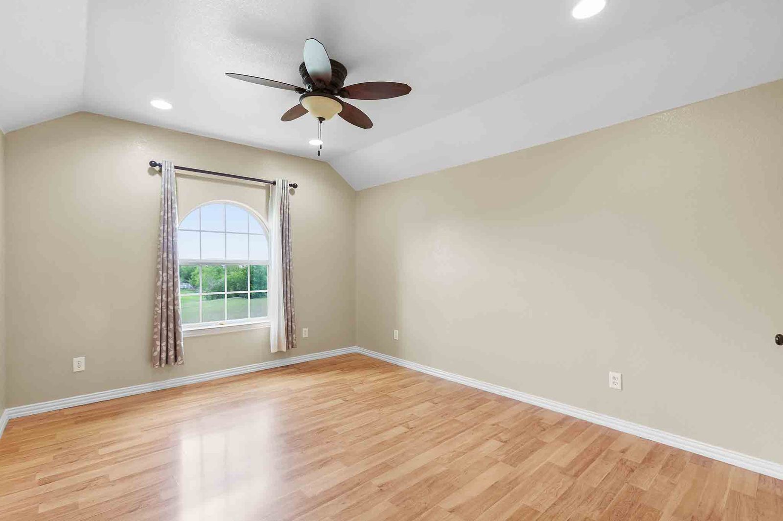 323 Woodbrook Trail Buda, TX 78610 - Photo 21 of 40 Spacious room featuring wood-finish flooring, an arched window, a vaulted ceiling with recessed lighting, and a ceiling fan
