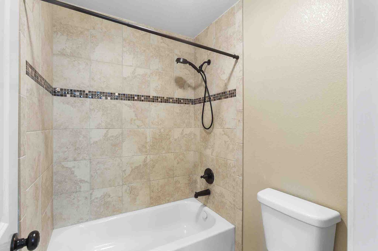 323 Woodbrook Trail Buda, TX 78610 - Photo 25 of 40 Jack-n-Jill bathroom features bathtub and shower combination featuring neutral-toned tile surround with a decorative mosaic accent band