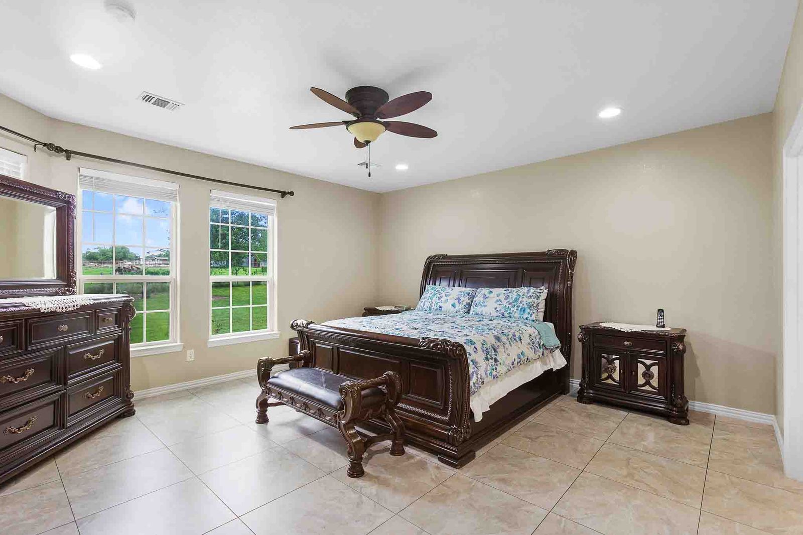 323 Woodbrook Trail Buda, TX 78610 - Photo 33 of 40 Spacious primary bedroom featuring light-toned walls, tile flooring, and a ceiling fan with integrated lighting
