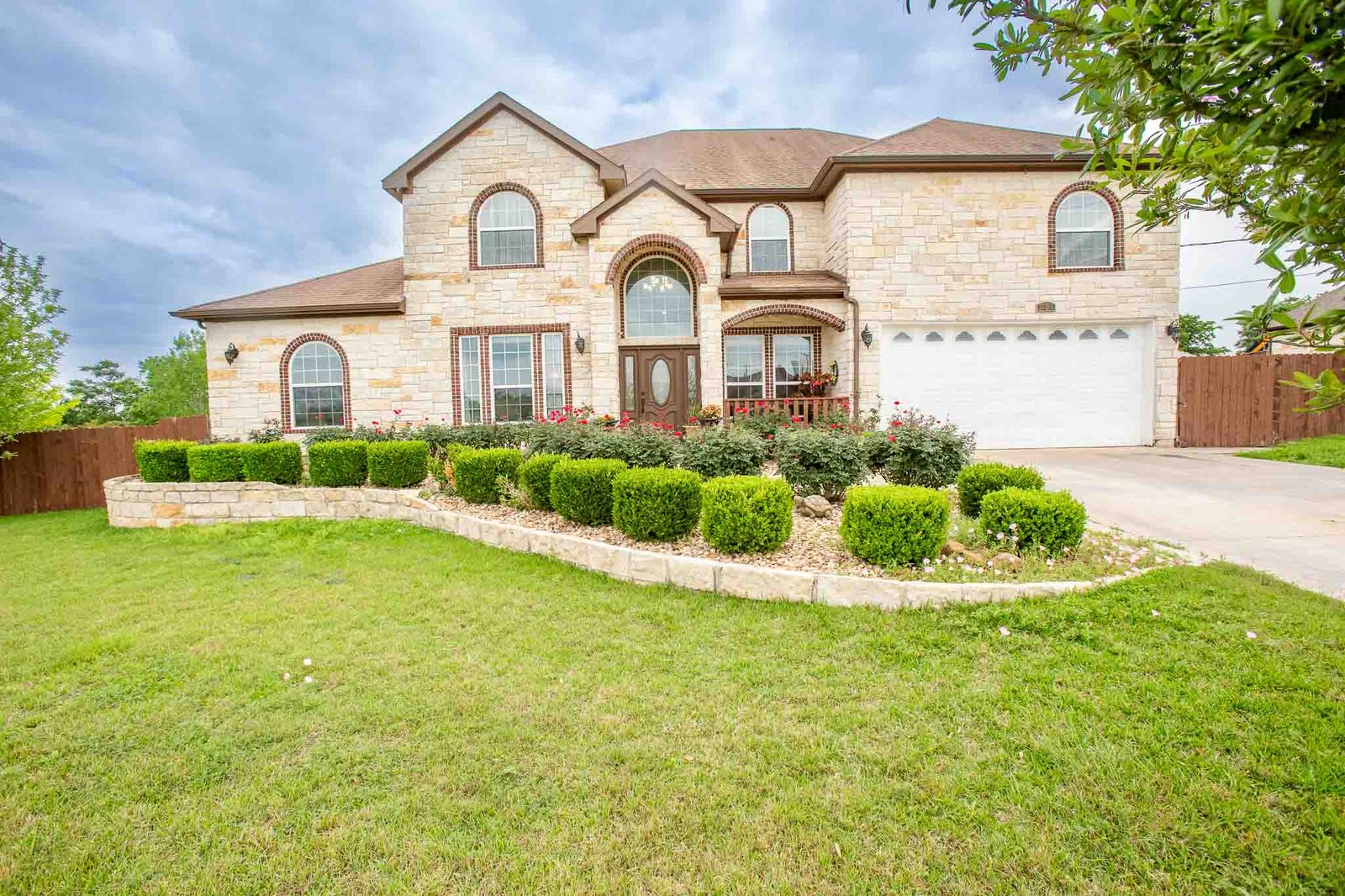 323 Woodbrook Trail Buda, TX 78610 - Photo 39 of 40 Stone facade residence featuring arched windows and a two-car garage