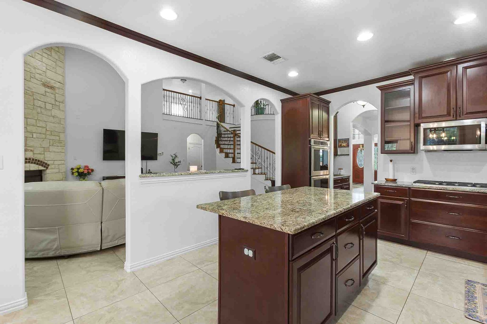 323 Woodbrook Trail Buda, TX 78610 - Photo 6 of 40 Spacious kitchen featuring dark wood cabinetry, a central island with a stone-finish countertop, and stainless steel appliances