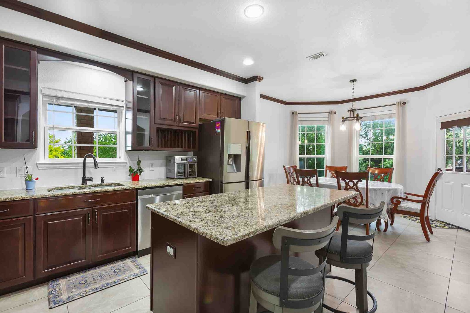323 Woodbrook Trail Buda, TX 78610 - Photo 8 of 40 Beautiful kitchen featuring wood cabinetry, granite countertops, stainless steel appliances, and tile flooring