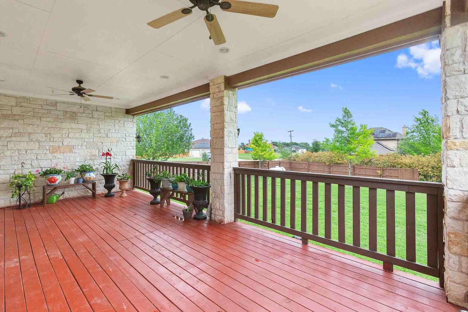 323 Woodbrook Trail Buda, TX 78610 - Photo 9 of 40 Covered outdoor patio with a red-stained wood-finish floor and stone veneer walls