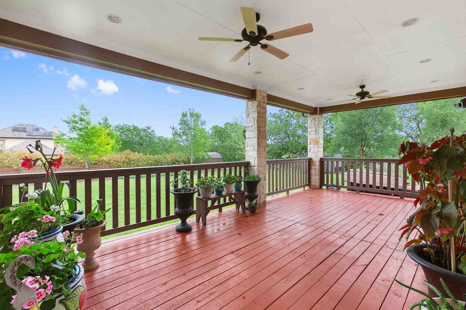 323 Woodbrook Trail Buda, TX 78610 - Photo 10 of 40 Expansive covered patio featuring wood plank flooring, stone pillars, and multiple ceiling fans