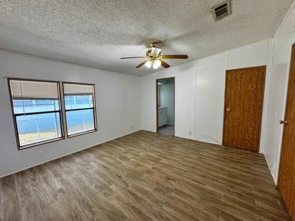 a view of empty room with wooden floor and fan