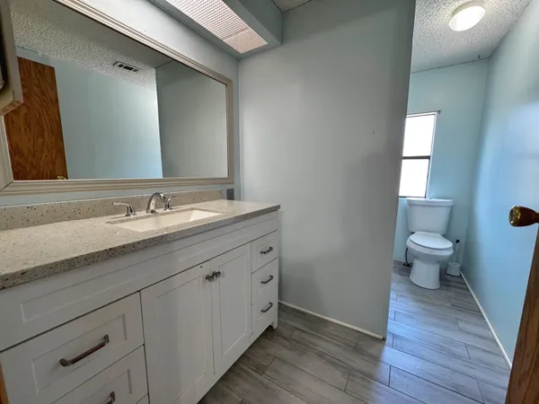 a spacious bathroom with a double vanity sink a toilet and a mirror