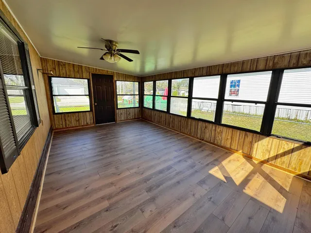 an empty room with wooden floor and windows