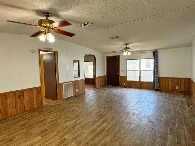 a view of an empty room with window and wooden floor