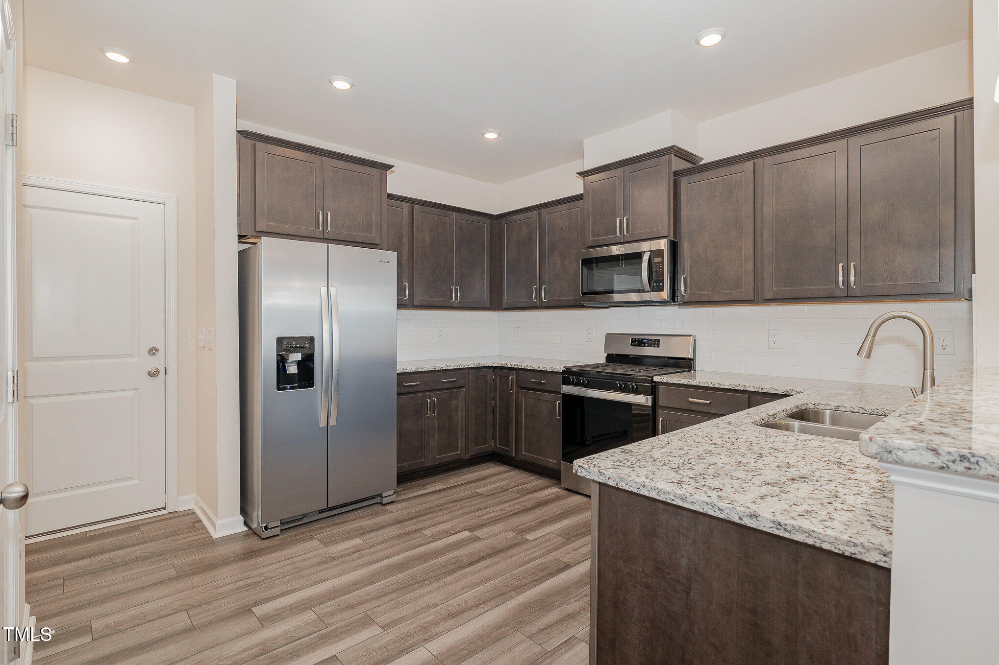 5706 Kalamata Drive Raleigh, NC 27603 - Photo 6 of 25 a kitchen with granite countertop a refrigerator and a stove top oven